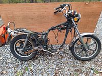 Side view of vintage 1984 Kawasaki KZ250W motorcycle frame showing wear, missing seat and fuel tank.