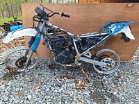 Side view of motorcycle salvage lot showing frame, engine, wheels, and rear body frame.