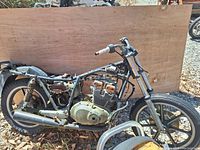 Side view of Suzuki GS400E motorcycle frame with engine, exhaust, rear wheel, and handlebar grips.