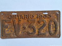 Photo of the first 1933 Ontario license plate with embossed number FV 520, showing heavy rust and wear.
