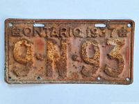 Front view of the rusted 1937 Ontario license plate showing embossed details and rust spots.