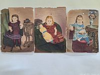 The trio of antique paintings laid out side by side showing the three young girls each in separate artistic portraits, with visible paint wear and edge tear.