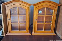 Front view of two matching wooden display cabinets with arched glass grid doors and metal knobs.