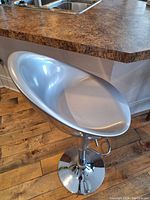 Silver adjustable height swivel bar stool next to kitchen counter, showing seat and base clearly.