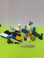Collection of 14 men's themed AVON decanters on green cloth background, showing variety of designs and colors