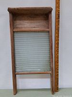 Full front view of antique washboard showing wooden frame and textured glass surface with crack visible.