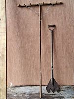 Full view of the hay rake and hay cutting tool side by side against a wooden background.