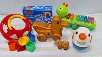 Front view photo showing the Fisher Price Shape Sorter Ball, wooden duck with smaller duckling, Fisher Price Pairs game box, Weeble Wobble Roly Poly Bird, and VTech xylophone