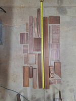 Overhead photo showing 22 dry black walnut wood pieces laid out with measuring tape for scale