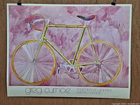 Frontal full view of watercolor painting showing entire bicycle on pinkish-purple background with signature and text at bottom edge.