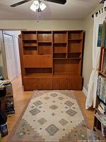 Full front view of two assembled teak wall units side by side, showing base cabinets and upper shelving sections.