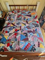 Full view of quilt spread out on a bed showing patchwork design and size.