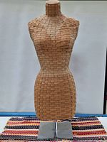 Front view of the vintage woven leather mannequin bust showing woven leather pattern and stable square metal base.