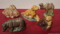 All six Wade ceramic animal figurines including a beige bunny, Irish Setter puppy, Bactrian camel, rhinoceros, beaver, and small animal figure shown from the front.
