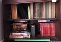 Shelf with multiple hardcover history and art books of varying colors, stacked and arranged vertically and horizontally.