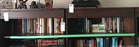 Books on shelves with titles including Titanic, Anne Frank's Diary, and soft cover novels by Joanna Trollope and Cecelia Ahern. Various sizes and colors visible.