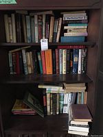 Overall view of three shelves filled with hard and soft cover books