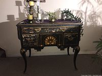 Full view of the black wooden cabinet with gold accents, showing overall condition and top surface with decorative items.