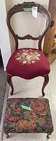 Full view of dark wood side chair with floral needlepoint seat and matching footstool with floral tapestry upholstery and metal legs.