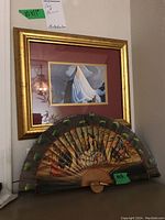 Framed art print measuring about 10x11 inches with gold frame and reddish mat, featuring a white-draped figure against a muted blue sky background, hanging on a wall.