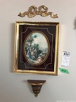 Framed print with velvet matte and oval classical outdoor scene, small ceramic wall shelf below it