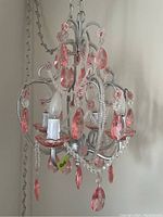 Front and side view of metal swag lamp with pink crystal accents and four candelabra bulbs