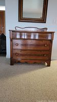 Front view of the wooden chest of drawers with attached mirror.