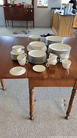 Full display of the German china set on wooden table including plates, cups, saucers, and bowls.
