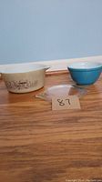 Two Pyrex bowls and a glass lid on wood floor, front view
