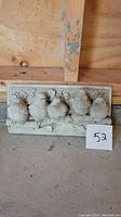 Concrete decorative plaque with five birds on a perch, showing detail and condition.