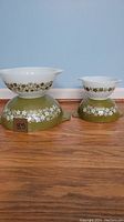 Side view showing two bowls, exterior avocado green and white floral Crazy Daisy pattern