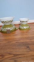Front view of two Pyrex Crazy Daisy mixing bowls with Avocado green base and white floral design, stacked to show pattern clearly.