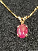 Close-up of the red stone pendant on gold chain showing details of the pendant stone and setting.