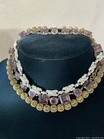 Three vintage choker necklaces displayed on black bust, showing gold-tone beads, amethyst-colored glass stones, and clear rhinestone designs.
