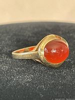 Front angled view of 8Kt gold ring with rounded cabochon carnelian stone showing deep reddish-orange color and polished gold band.