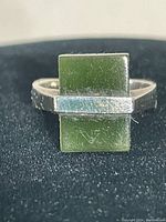 Front view of the Art Deco sterling silver ring with rectangular green stone on black background