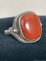 Close-up of the front of the ring showing the large rectangular orange stone with roped silver bezel setting.