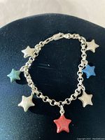 Full view of the sterling silver bracelet laid out with multi-colored star-shaped charms attached.