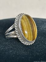 Close-up photo showing the oval tiger eye stone in a sterling silver setting with rope trim detailing.