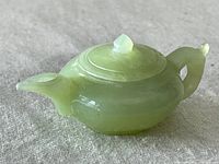 Side view of small jadeite miniature teapot with lid in place, showing overall shape and color