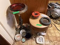 Wide view showing standing ashtray, multiple glass and ceramic ashtrays on floor, and vinyl footstool.