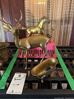 Overall display of three brass animal figurines and soap dish on shelf