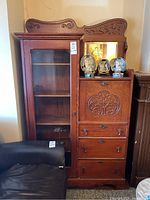 Full view of tall oak cabinet with glass door on left and drop-front bureau with three drawers on right.