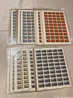 Sheets of various commemorative Canadian stamps sealed in plastic, arranged in two groups.