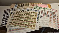 Multiple uncut stamp sheets fanned out on white table
