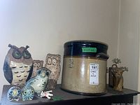 Wide view showing the full 3-gallon crock and styled owl figurines of various sizes placed on top around it.
