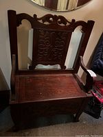 Angled view showing carved backrest, armrests and hinged seat