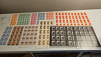 Overhead view of multiple folded stamp sheets including colored definitives, red and gold Lunar New Year discs, and Trudeau portrait sheets