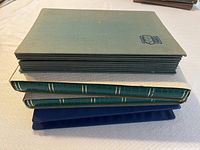 Four stamp albums stacked, showing varied colors and textures of covers.