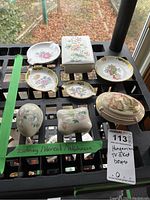 Overall view of nine porcelain trinket boxes and dishes arranged on crate